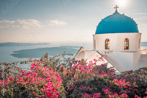 Iconic blue-domed church and bougainvillea overlooking the caldera and aegean sea