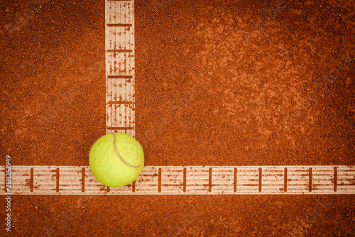 Tennisball auf der Kreuzung weißer Spielfeldlinien eines roten Sandplatzes aus der Vogelperspektive mit viel Freiraum für Text.