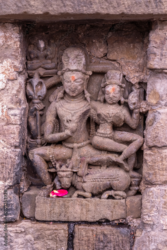 Obraz premium Stone sculpture depicting Shiva seated on his mount, with a floral offering. Baijnath Temple, Kangra District, Himachal Pradesh, India.
