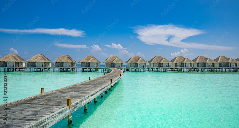 Fototapeta premium Maldives ocean overwater bungalows turquoise lagoon wooden jetty blue sky. Luxury tropical travel paradise honeymoon resort marketing. Sunny sky aqua clear water scenic wallpaper background design