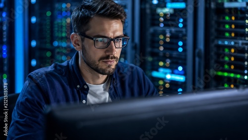 Portrait of Focused Young IT Professional Wearing Glasses Working at Desktop Computer in Modern Data Center Office