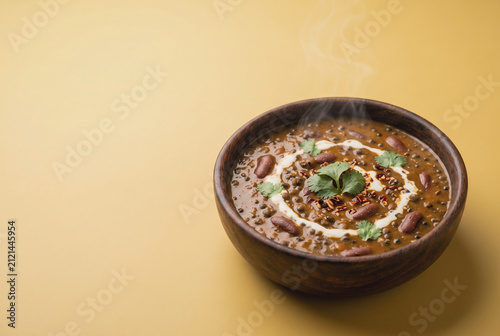 Creamy dal makhani in wooden bowl with steaming rustic presentation
