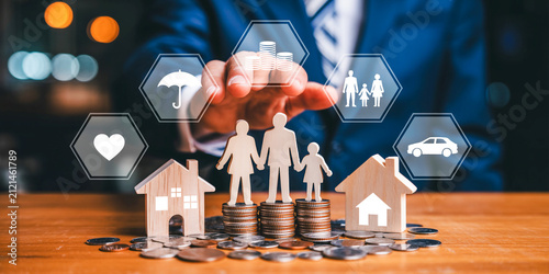 Professional businessman planning family financial security and insurance investment with coins and miniature houses