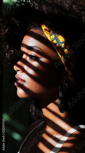 Artistic portrait in dramatic lighting with venetian blind shadows creating striking pattern across face wearing colorful headwrap, moody atmospheric photography