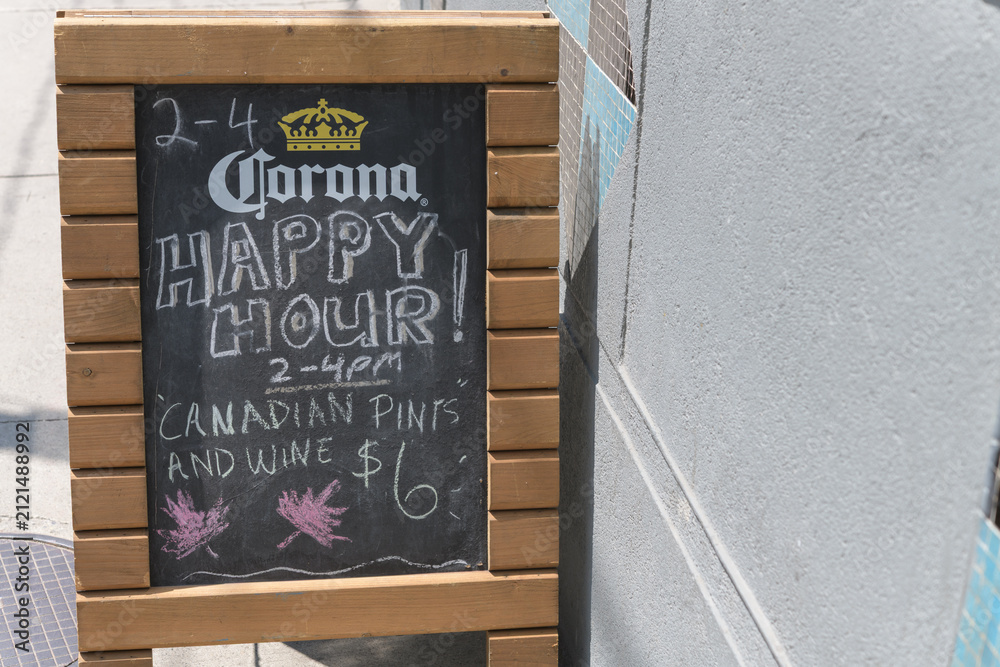 Fototapeta premium a-frame sidewalk chalkboard sign with Corona brewery sponsored signage outside a pub on Queen West, Toronto