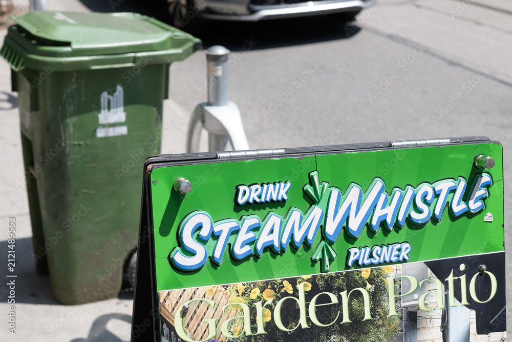 Fototapeta premium Steam Whistle brewery branded a-frame sign outside a pub on Queen West, Toronto