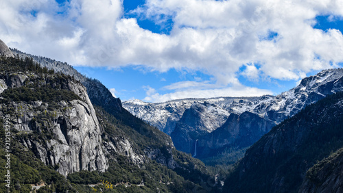 Obraz na plátne Panoramic view across Yosemite Valley in California featuring snow-covered granite cliffs, Bridalveil Fall and dramatic winter clouds