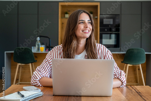 Принти на полотні Young woman confidently looking away from her laptop while working remotely in a