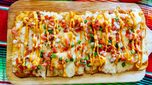 Obraz na plátně Delicious flatbread topped with cheese, vegetables, and sauce served on a wooden