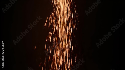 A close-up view of bright, hot sparks raining down against a dark background.