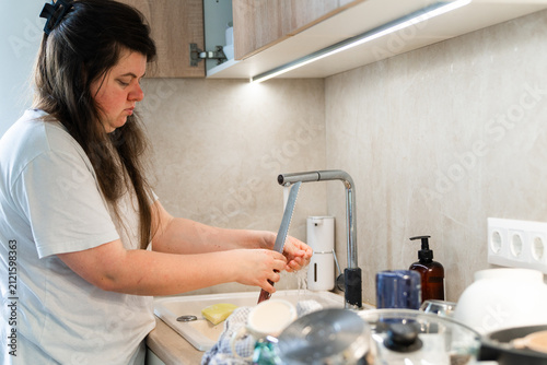 Konstfotografi Woman washing dishes in the sink in the kitchen under running water