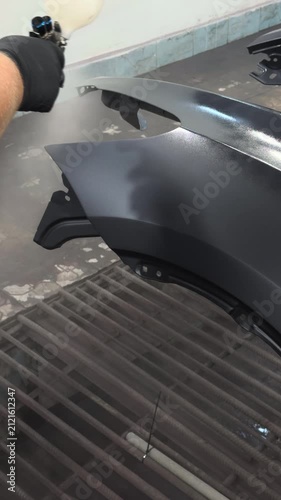 Professional auto body painting with spray gun in a workshop