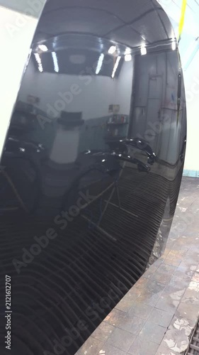 Automotive paint booth with freshly painted car parts reflecting lights