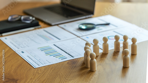 фотографія Business meeting with wooden figures representing people and financial reports