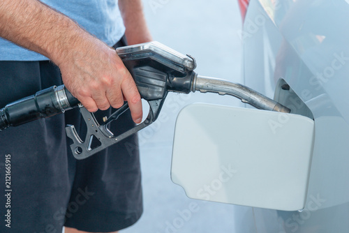 Fotografía person fueling a diesel car at a gas station, close-up of nozzle in fuel tank, c