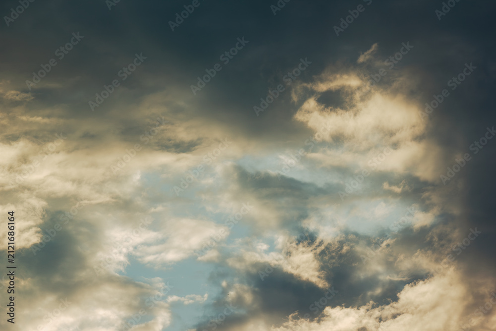 Obraz premium Dramatic cloudy sky with warm sunlight breaking through storm clouds