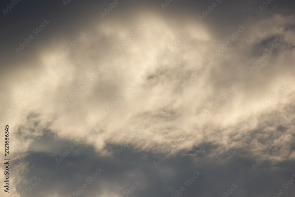 Fototapeta premium Dramatic dark storm sky illuminated by warm sunlight texture background