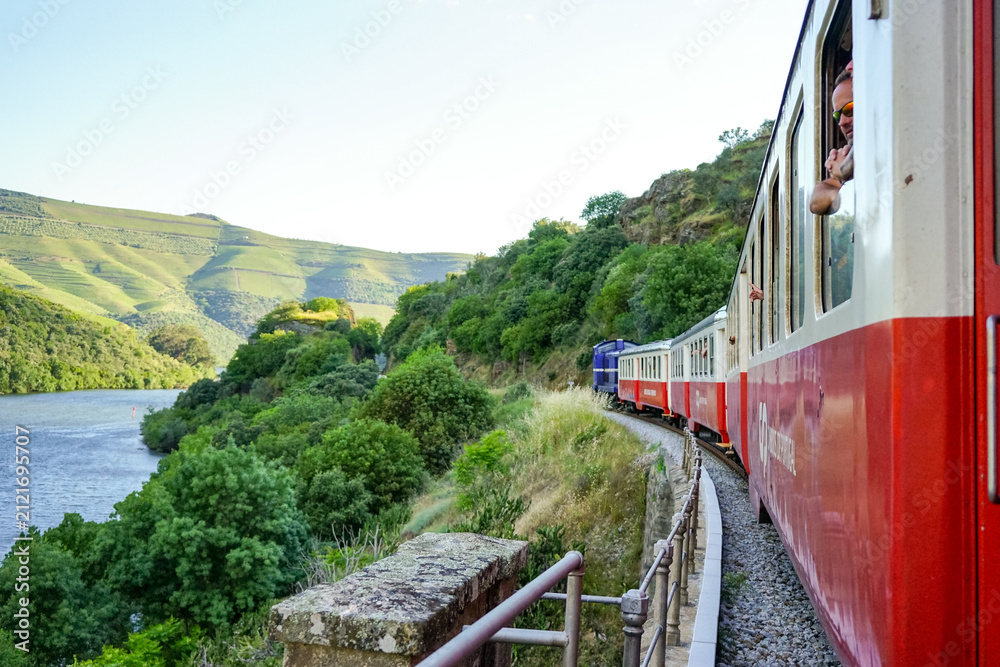 Obraz premium Scenic view from a passenger window of a regional train traveling along the iconic Douro Line in Portugal
