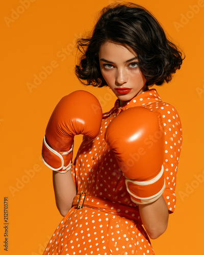 Surreal Retro Woman in Polka Dot Dress Wearing Orange Boxing Gloves