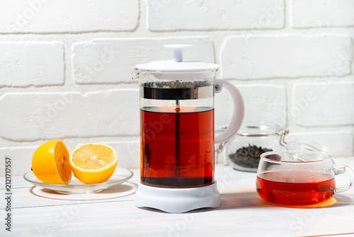 fresh black tea with lemon brewed in a French press on white background