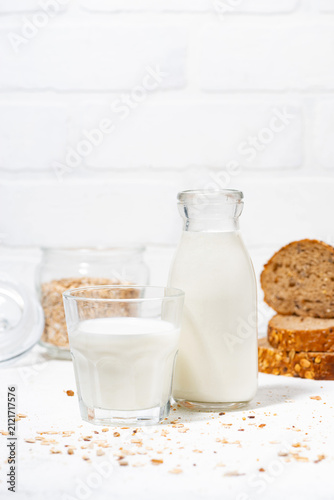 fresh milk and whole grain bread slices on white table