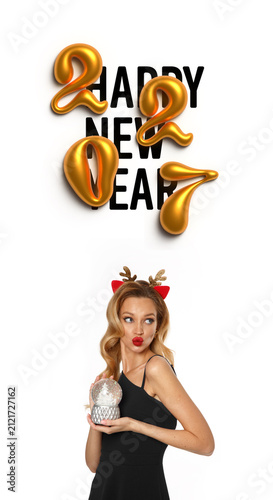 Vertical photo banner with young adult white blonde woman with black dress, red lips, carnival deer horns on head holding Christmas ball in hand, text Happy New Year and golden letters 2027 on white