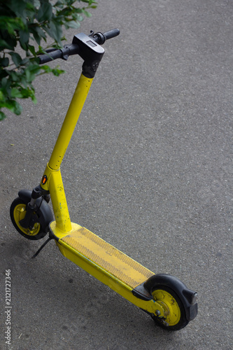 Vertical photo. Top view. Yellow electric scooter without logo on city street parking lot. Concept of kicksharing, rent transport, kick scooter sharing, road trip, job, eco, green power, zero waste