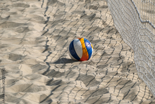 Beach volleyball beside net casting shadows on sand