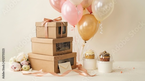 Cardboard boxes stacked high next to cupcakes in individual containers make an appealing display for a bakery shop.