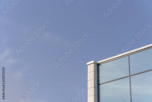 A modern glass facade of a commercial office building corner. A minimalist corporate architecture background with vast copy space.