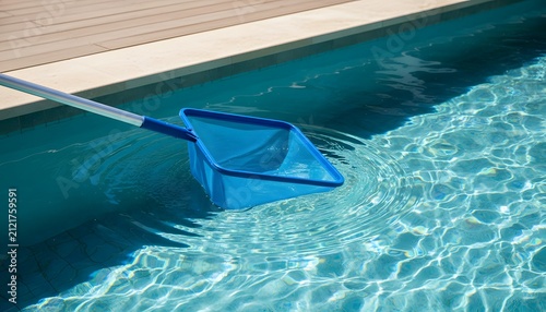 A blue pool cleaning net skimming the clear water surface to remove floating leaves and debris for luxury hotel resort service and backyard maintenance concept