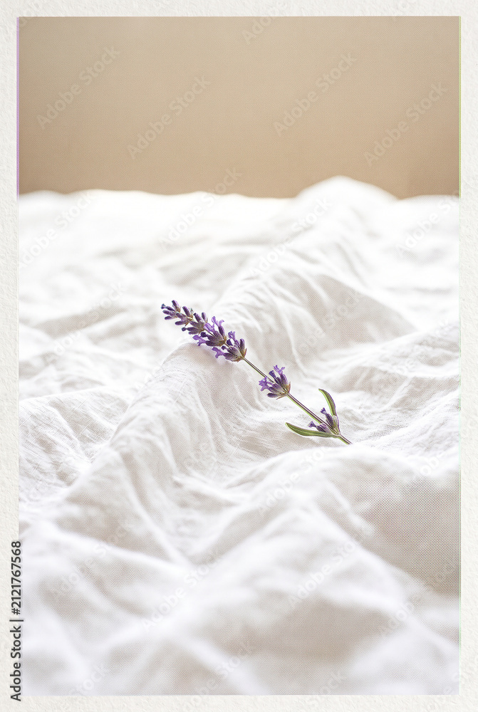 Obraz premium Single lavender sprig on white linen in high-key light.