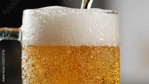 Golden craft beer pours dynamically into a frosty glass mug, capturing the rising thick white foam head and effervescent carbonation bubbles under clean, professional, and refreshing studio lighting.