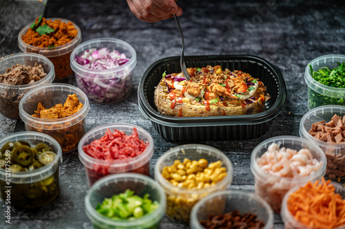 Baked potatoes with cheese, herbs, meat and butter. Copy space background. BBQ or steakhouse side dish favorite with tomato beans, cheddar cheese, bacon.