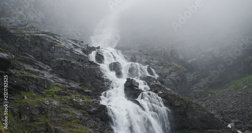 Stigfossen waterfall flowing down misty mountains in norway