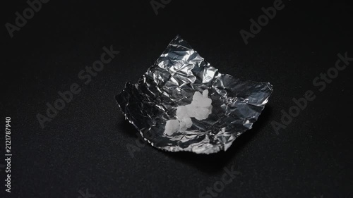 Fentanyl or crystal meth is widely used stimulant in current drug trend. Methamphetamine mixed with fentanyl as crystals in foil. Illicit substance in foil bag for transportation and sale.