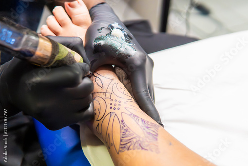 Tattoo artist working on foot instep with floral outline