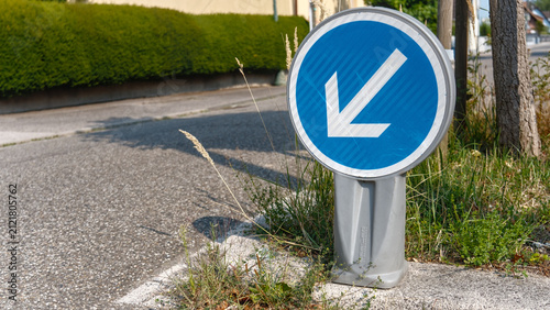 Blue and white street sign with arrow on sidewalk