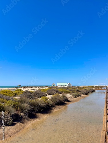 View over dunes and brackish land to white turquoise beach huts at the Playa de Camposoto, Chiclana de la Frontera, San Fernando and Cadiz, Andalusia, Spain