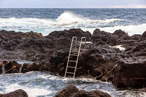 Natural ocean swimming pool at Ponta da Ferraria on the volcanic coast of Sao Miguel Island, Azores, Portugal, with Atlantic waves and dramatic evening sky
