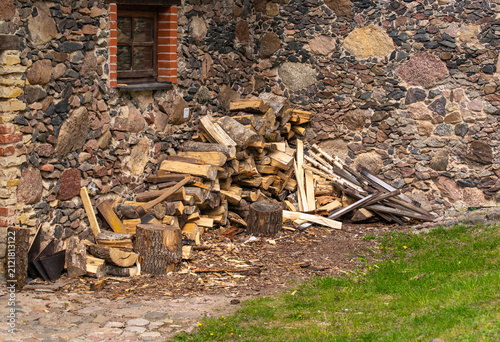 large stack of firewood with axe resting on top in rustic outdoor setting.