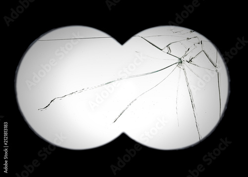 View through a broken binocular lens with prominent cracks and a dark vignette effect. The damaged glass creates a distorted, obstructed, and aged visual texture for dramatic effect.
