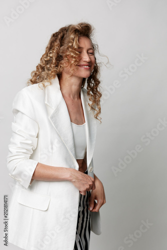 Fotografía A mature woman in a white blazer smiles softly, highlighting natural skin and effortless style in a candid portrait with warm lighting and a relaxed mood