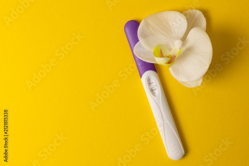 Bild auf Leinwand Positive Pregnancy Test with White Orchid on Color Background