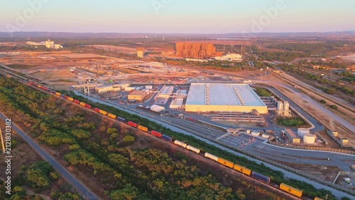 Data center building, freight train and expansion site under construction near the coastline in Portugal at sunset. Green landscape. Aerial view. Moving backwards