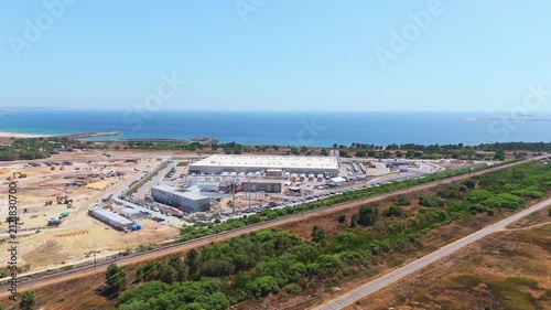 Data center building and expansion site under construction near the coastline in Portugal. Green landscape and Atlantic ocean. Aerial view. Moving forward