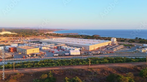 Data center building and expansion site under construction near the coastline in Portugal at sunset. Green landscape and Atlantic ocean. Aerial view. Orbiting