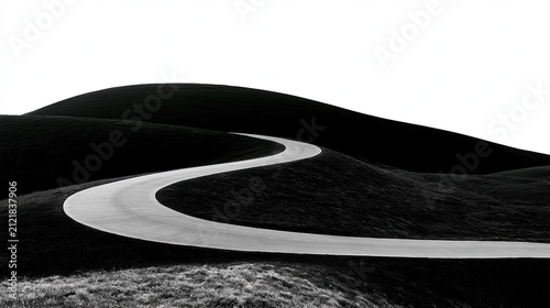 A winding asphalt road cuts through dark, rolling hills under a bright sky