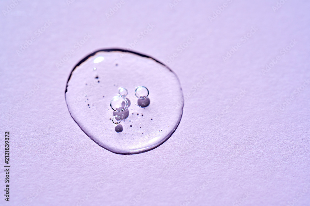 Fotografie Cosmetics serum drop on purple background texture