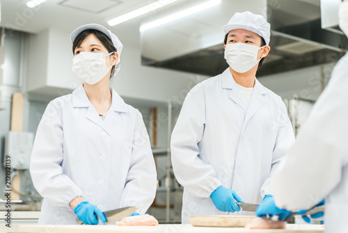 Fotografie Male and female staff in chef's coats preparing fish (cooks, chefs, fresh food m